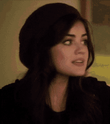 a close up of a woman wearing a hat and a black shirt