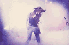 a woman is dancing in front of a microphone in a dark room