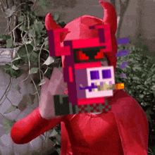 a person in a red devil costume with horns and a skull on their head .