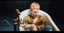 a man is sitting in a bathtub with water coming out of it and smiling .