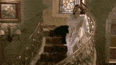 a woman in a white dress walking down a set of stairs
