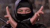 a man in a ninja costume is making a cross with his arms