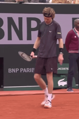 a man holding a tennis racquet in front of a bnp parie banner