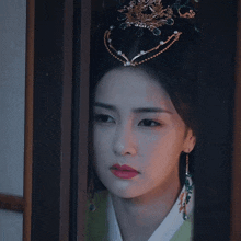 a woman with a tiara on her head is looking out a window
