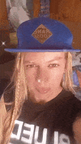 a woman is wearing a blue hat and a black shirt with the word jesus on it