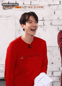 a young man in a red shirt is laughing while holding a white towel .