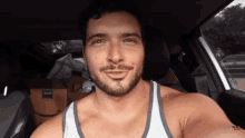 a man with a beard is smiling while sitting in a car .