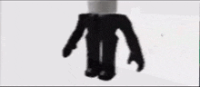a black roblox character with a white head and black pants is standing on a white surface .