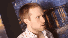 a man is standing in front of a painting and making a silly face