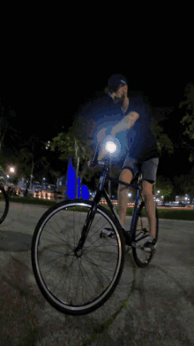 a man is riding a bike down a sidewalk at night