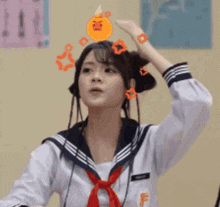 a girl in a sailor suit is adjusting her hair while wearing headphones .