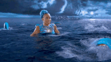 a woman in a blue dress is swimming in the water