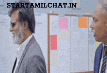 two men are standing in front of a board and the website starttamilchat.in is visible