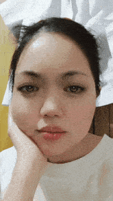 a close up of a woman 's face with a hand on her chin