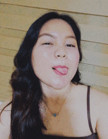 a woman sticking her tongue out and wearing a necklace that says love