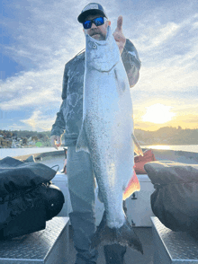 a man on a boat holds a large fish in his hand