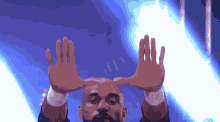 a bald man with a beard is holding his hands up in the air