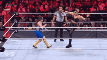 two women are wrestling in a wrestling ring with a referee watching