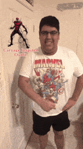 a man wearing a marvel t-shirt with a picture of carnage on the wall behind him
