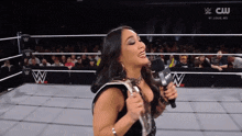 a woman is holding a microphone in a wrestling ring with a cw logo in the background
