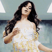 a woman in a yellow floral dress is dancing in a room .