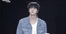 a young man in a blue jacket stands in front of a sign that says ' bts / inkita ' on it