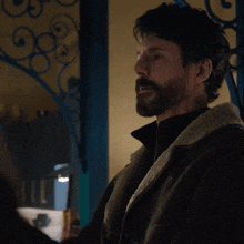 a man with a beard is wearing a fur coat