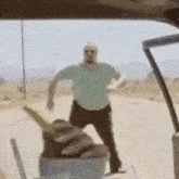 a man in a green shirt is standing on the side of the road .