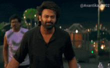 a man with a beard is standing in front of a sign that says avantika 0902