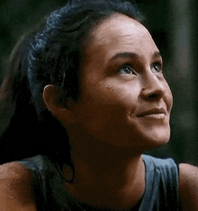 a close up of a woman 's face with a ponytail smiling .