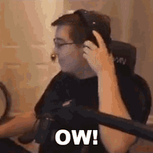 a man wearing headphones and glasses is sitting in a chair and talking on a cell phone .