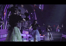 a woman in a black shirt and green skirt is singing into a microphone on a stage