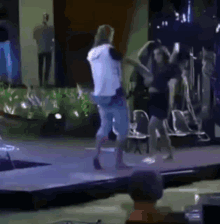 a group of people are dancing on a stage in front of a crowd of people .