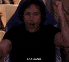 a man is sitting in a chair with his fist in the air and the word osa sranee is on the bottom of the image