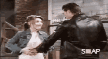 a man in a leather jacket is touching a woman 's stomach .