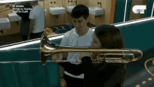a man and woman are playing a trombone in a bathroom .