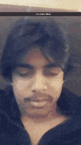 a close up of a man 's face with a mustache and a black jacket .
