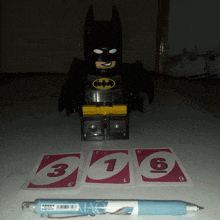 a batman figure sits on a table next to uno cards