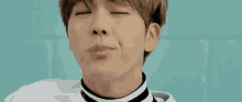 a close up of a young man making a funny face with his eyes closed and his mouth open .