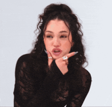 a woman with curly hair is wearing a black lace top and rings