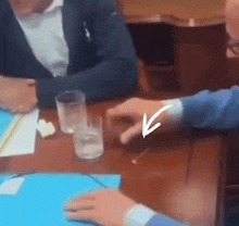 a person sitting at a table with a arrow pointing to a glass