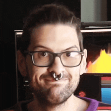 a man wearing glasses and a nose ring makes a funny face