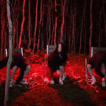 a group of people are dancing in a dark forest with red lights