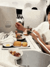 a person is sitting at a table with a plate of food and a bowl of nuts with the number 46 on it
