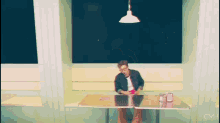 a man is sitting at a table in a diner looking at his cell phone