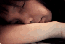a close up of a woman laying down with her head resting on her arm