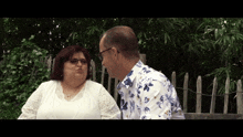 a man and a woman are sitting in front of a fence