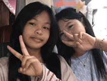two girls giving a peace sign in front of a sign that says " ava "