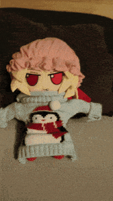 a stuffed doll wearing a sweater with penguins on it