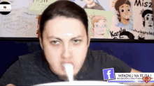 a man in a black shirt is drinking from a container with a facebook logo in the corner